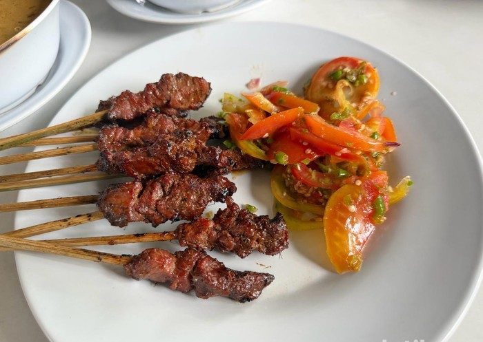 Seporsi sate maranggi khas Jakarta dengan daging sapi empuk, sambal tomat, acar segar, dan nasi putih di atas meja makan.